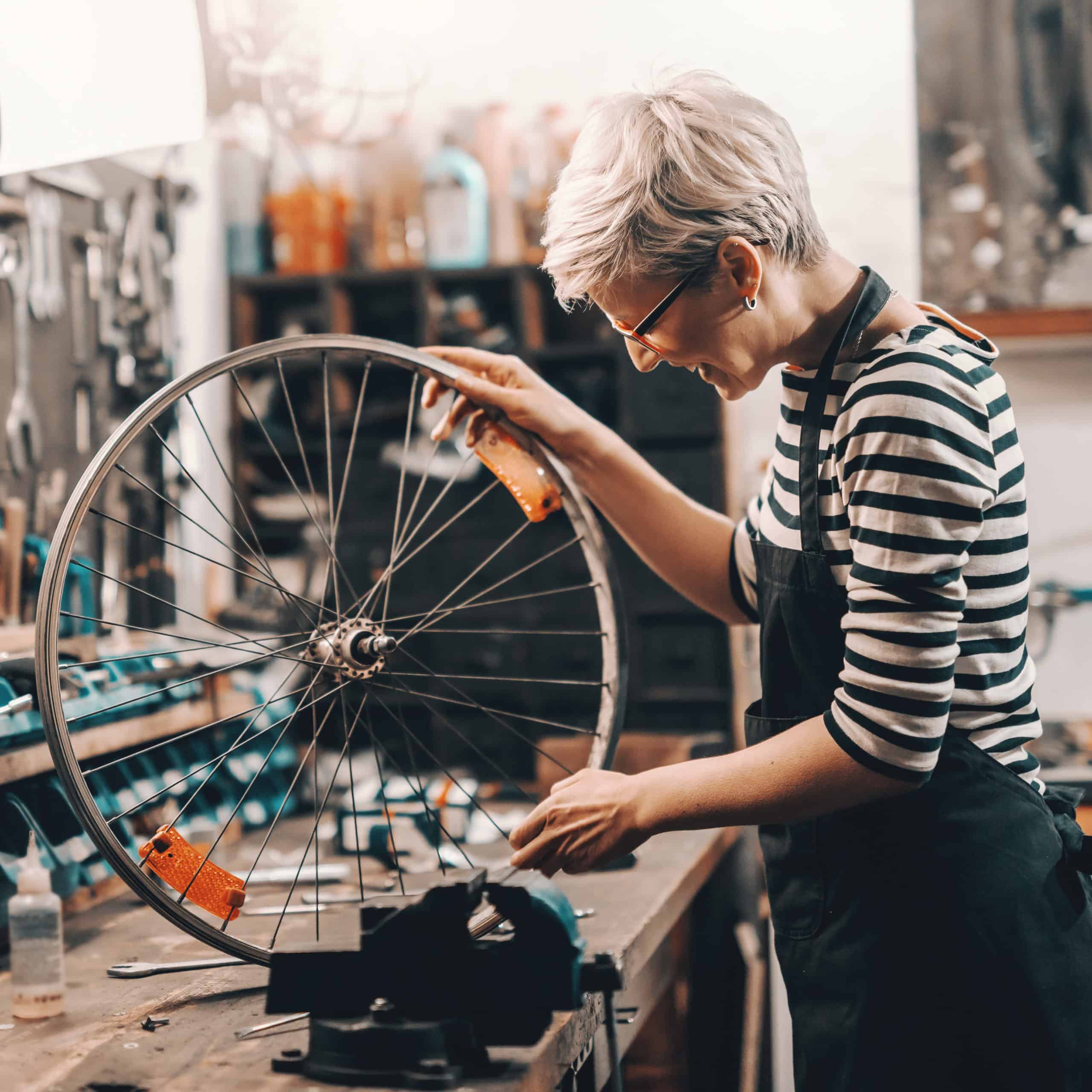 Female repairing a bicycle wheel.