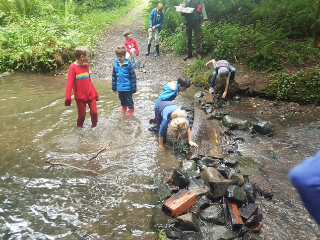 Children in shallow river building a  dam