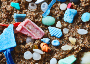 photo of colourful pieces on plastic on sand , including little round nurdles